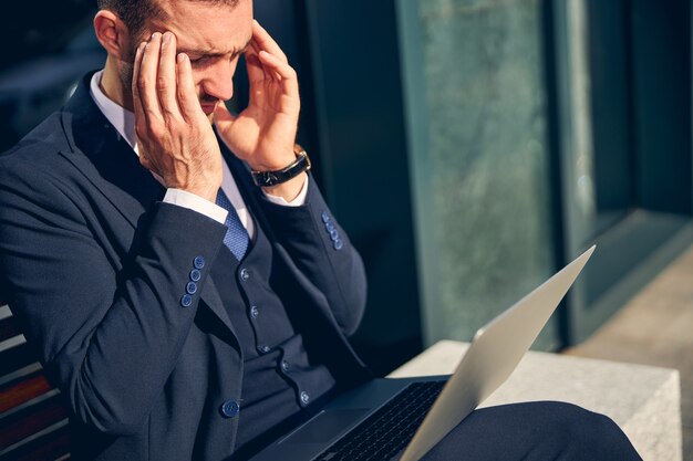 handsome-young-man-sitting-outside-with-laptop-knees-while-working-touching-head-pain_447912-273 Reembolsos abusivos: Justiça decide contra o Mercado Livre por prática irregular